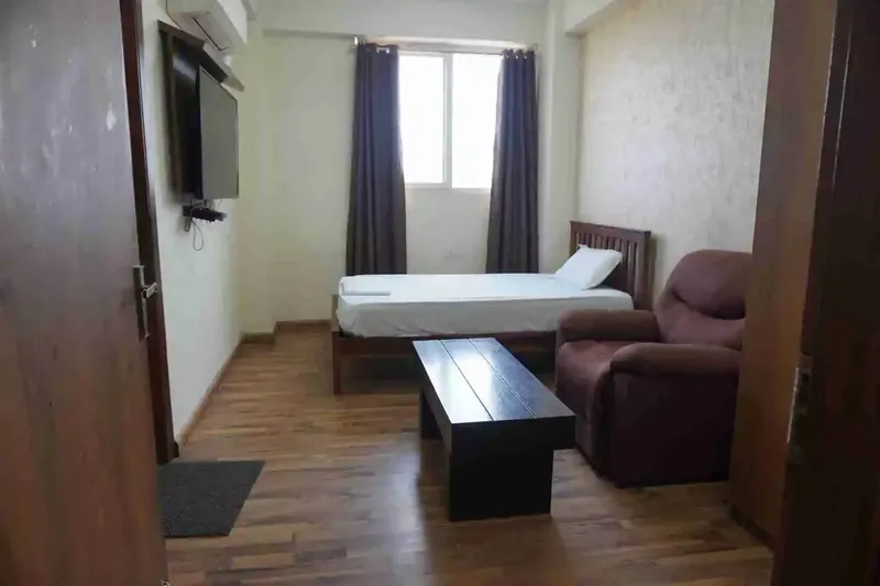 Patient room with a bed and seating at the Gurugram centre
