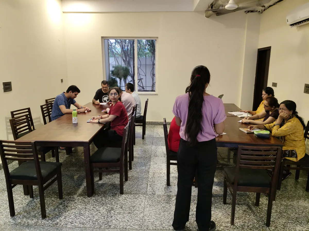 A counsellor leading a group around the table at the Mehrauli centre