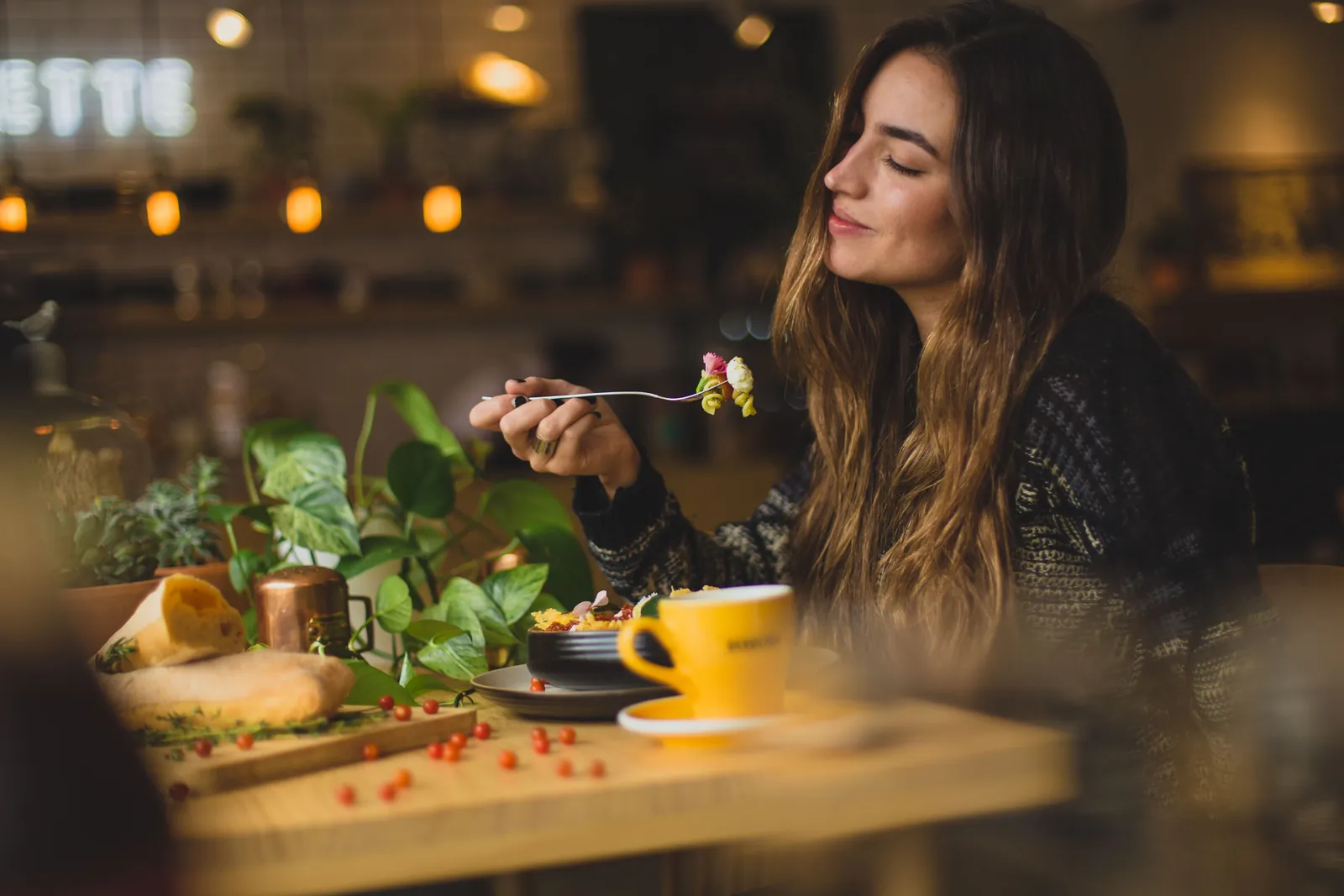Woman holding fork in front table
