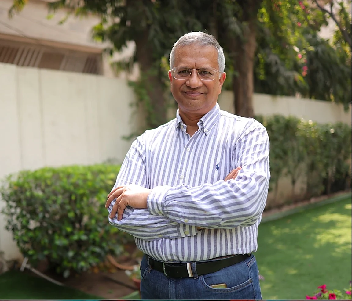 Dr. Gorav Gupta standing in his garden with arms folded, smiling.